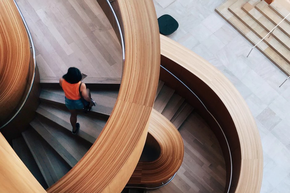A sweeping wooden staircase inside a contemporary gallery.